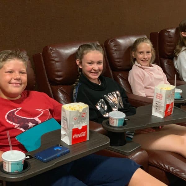 Three kids smiling at movie theater